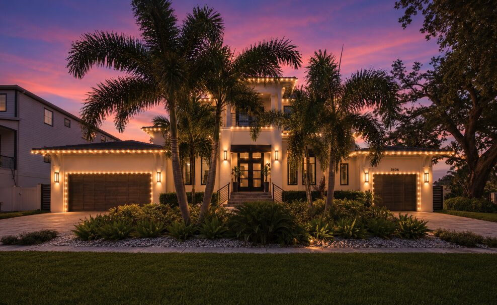 Coastal modern home framed by royal palms with warm white roofline lighting — Davis Islands, Tampa