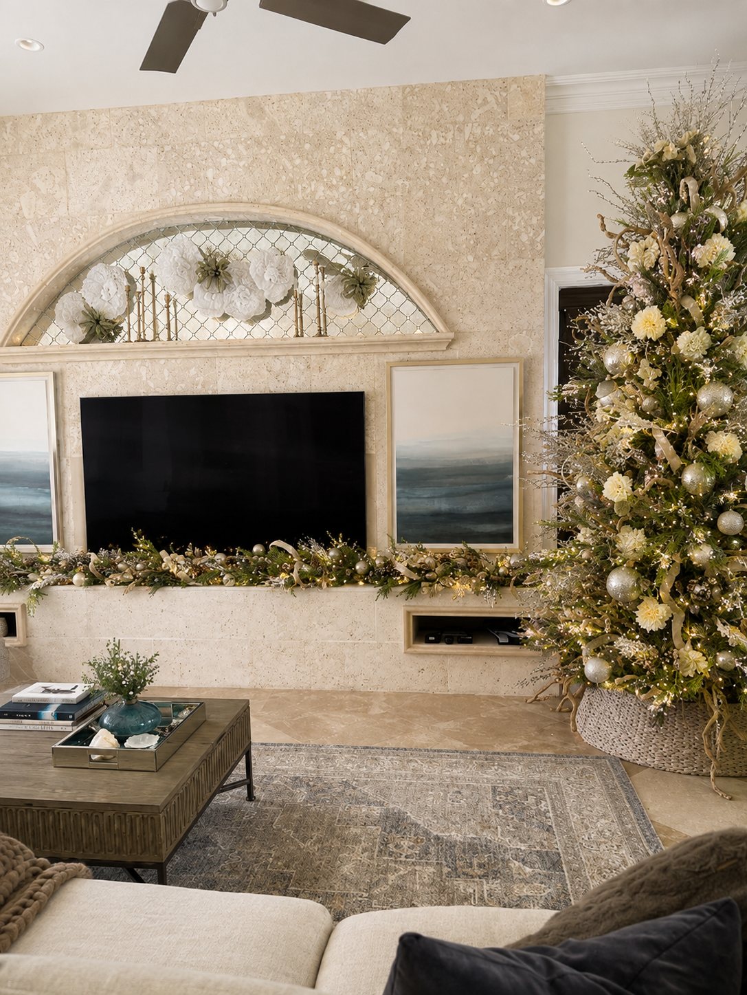 Living room Christmas tree with cream and gold ornaments beside a stone fireplace, styled by Light the Lights