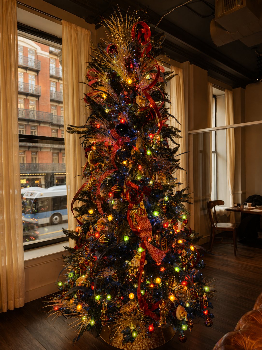 Jewel-tone Christmas tree with ribbon and ornaments beside a restaurant window, styled by Light the Lights