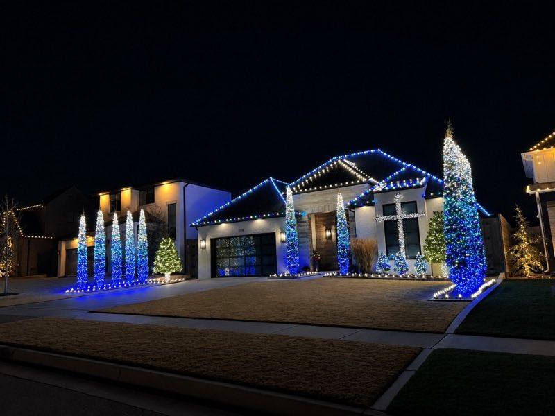 Modern home with blue and white holiday lighting and lit topiary trees, Land O' Lakes FL