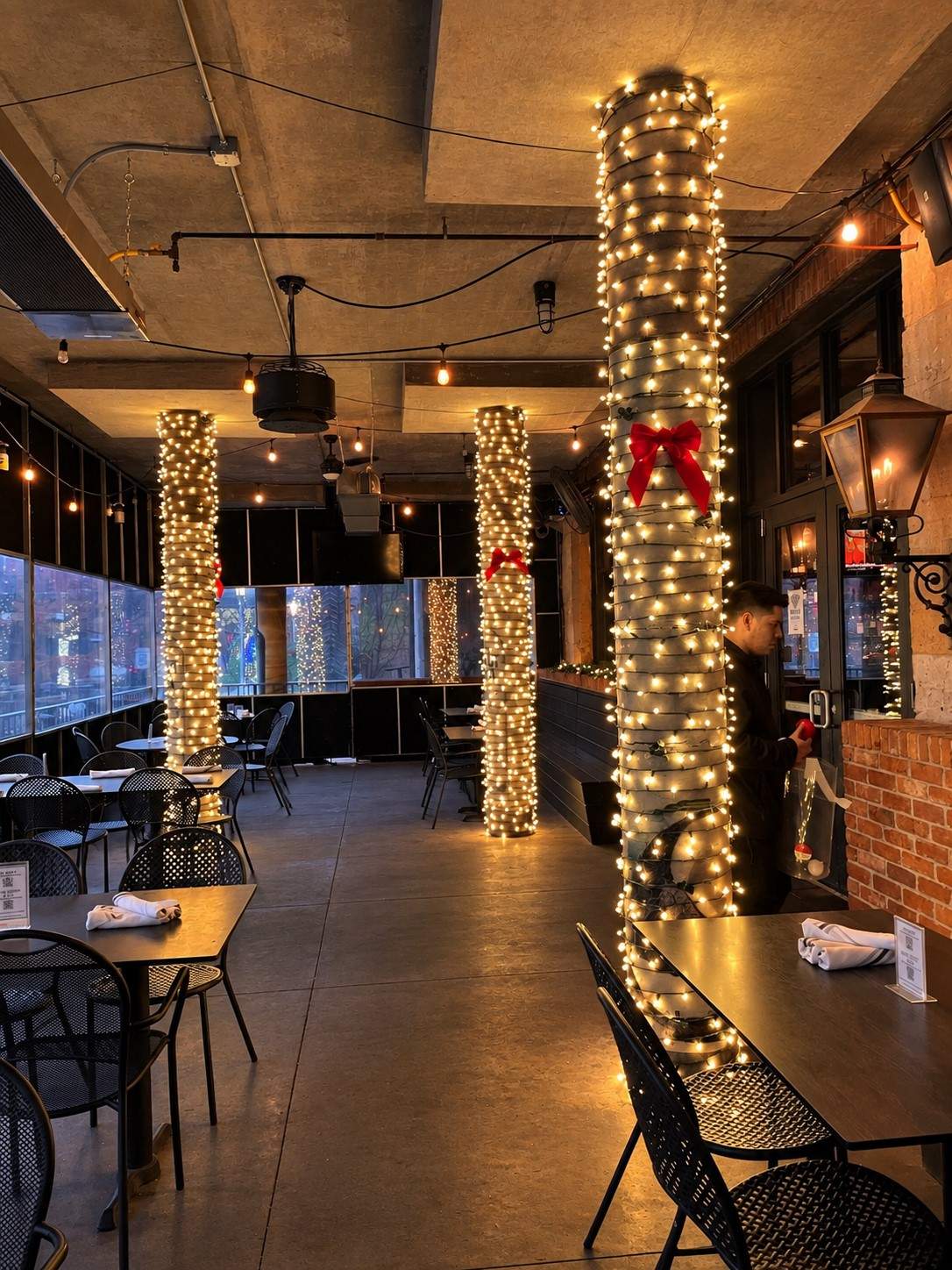 Restaurant patio columns wrapped in lights with red bows